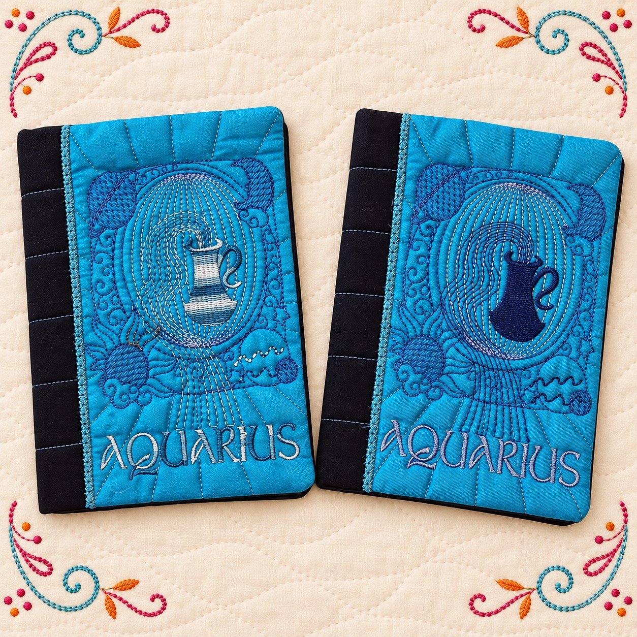 Two blue embroidered Aquarius notebook covers on a cream quilted background